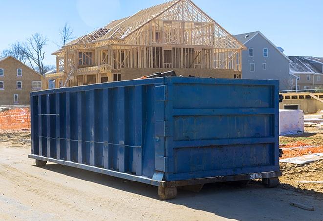 a residential dumpster at the end of a long driveway, awaiting disposal